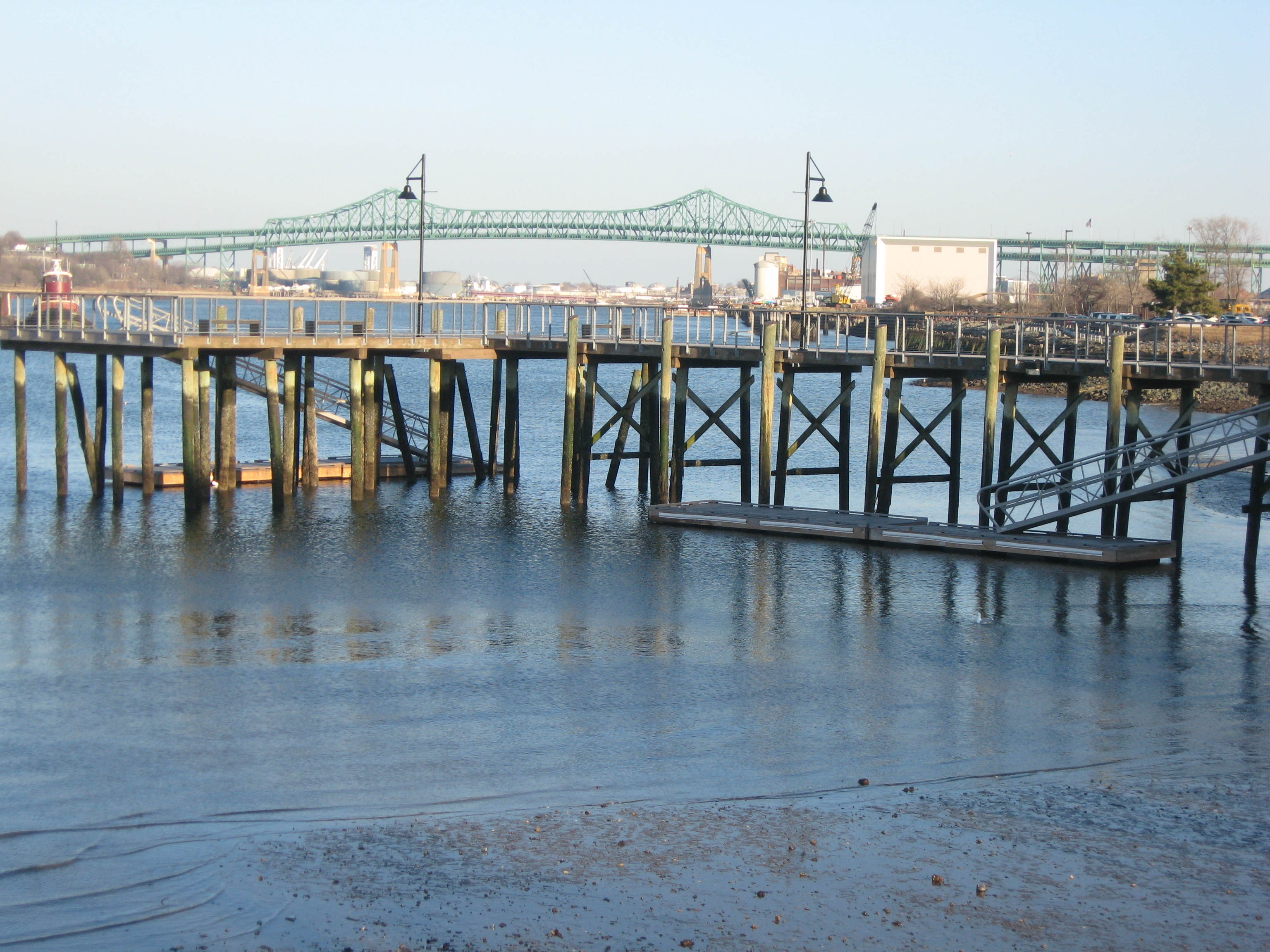 Low tide on the Mystic estuary with pier and Tobin bridge.